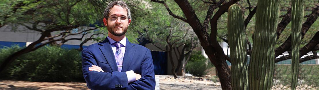 A paralegal student poses for a photo in a suit in a Pima West campus courtyard