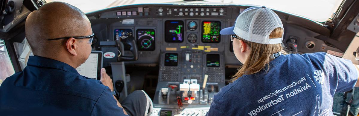 An Aviation student poses for a photo sitting on airplane at Pima's Aviation Center