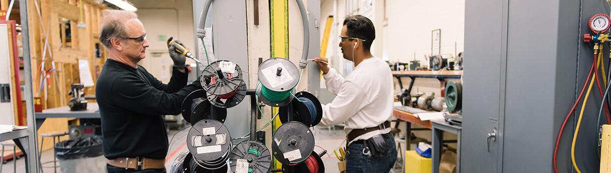 two students work on electrical equipment in a Pima Lab